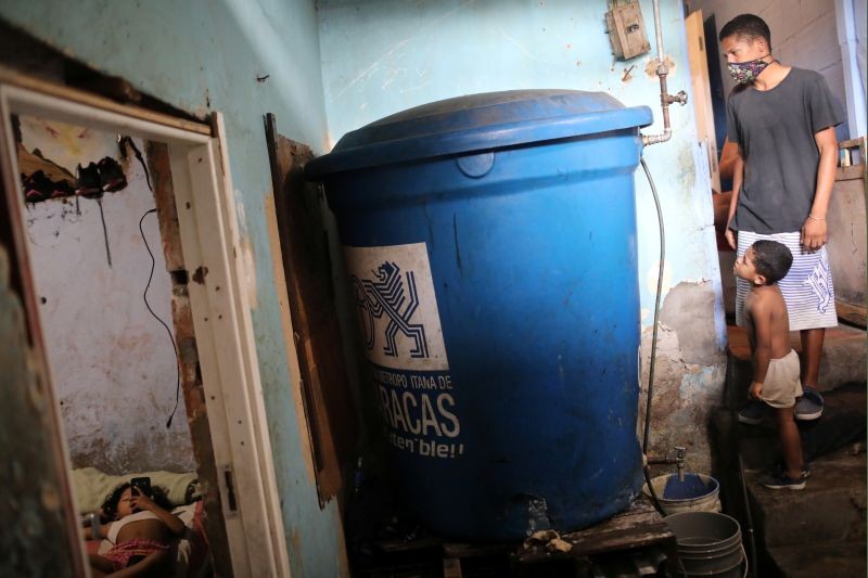 Inside his house, Henry checks the water level of his plastic tank, filled with water by a community-made pipe system that extract water that accumulated at a stalled tunnel construction project near El Avila mountain that borders the city of Caracas, Venezuela on August 8, 2020. (REUTERS Photo)