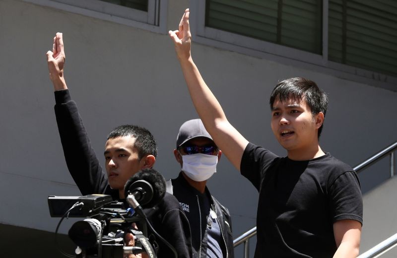 Pro-democracy leaders Tattep Ruangprapaikitseree and Panumas Singprom, flash the three-fingers salute as they are escorted by police officers after being arrested, at a police station in Bangkok, Thailand on August 26. (REUTERS Photo)