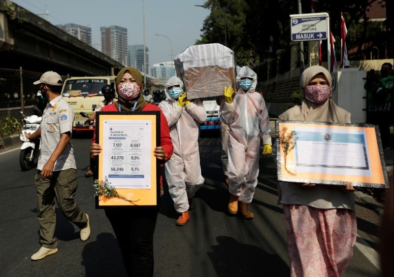 Government workers wearing protective suits carry a mock-up of a coffin of a coronavirus disease (COVID-19) victim as others carry signs displaying information about the number of COVID-19 cases on a main road to warn people about the dangers of the disease as the outbreak continues in Jakarta, Indonesia on August 28, 2020. (REUTERS File photo)