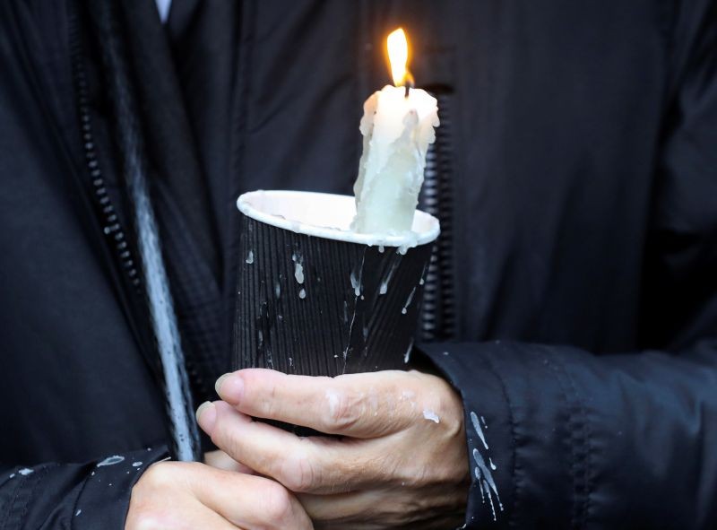 A mourner waiting for the funeral procession of John Hume holds a candle outside St Eugene's Cathedral in Londonderry, Northern Ireland on August 4, 2020.  (REUTERS Photo)