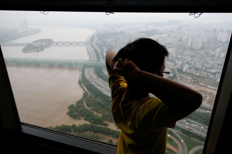 A boy looks down a flooded Han River park at an observatory platform in Seoul, South Korea on August 4. (REUTERS Photo)