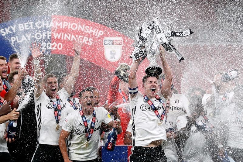 Fulham's Tom Cairney lifts the trophy as he celebrates promotion to the premier league with teammates after winning the match, as play resumes behind closed doors following the outbreak of COVID-19. (Reuters Photo)
