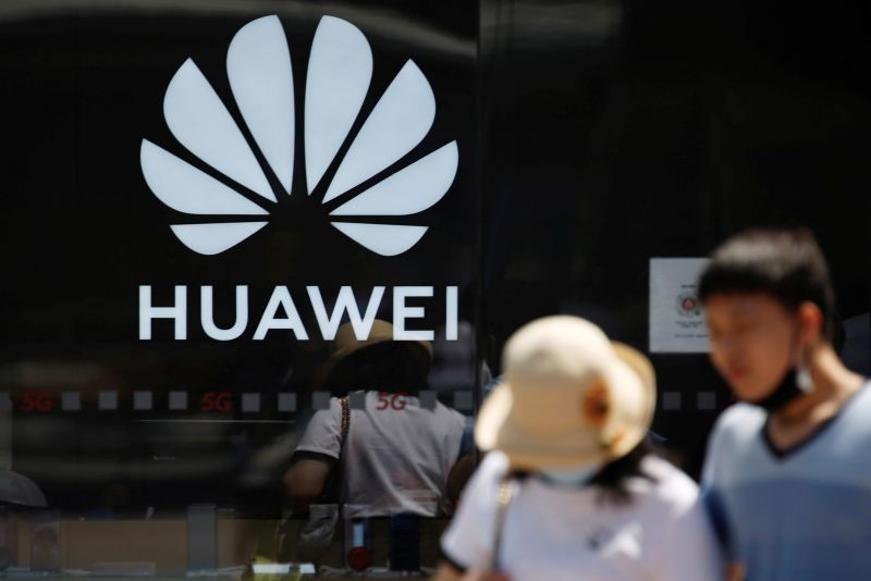 People walk past a Huawei logo on the facade of its store at a shopping complex in Beijing, China July 14, 2020. REUTERS/Tingshu Wang/Files