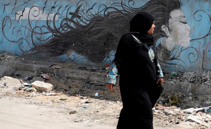 A woman walks past a mural depicting anti-sexual harassment message and reading "Woman is free" at a highway in Cairo, Egypt on September 3, 2018. (REUTERS File Photo)