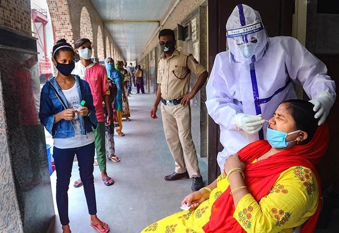 A medic collects samples from a woman in New Delhi.  PTI Photo