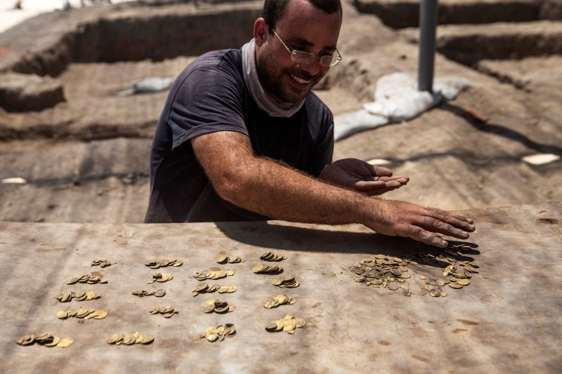 Israeli archaeologist Shahar Krispin counts gold coins, said by the Israel Antiquities Authority to date to the Abbasid dynasty, after its discovery at an archaeological site in Central Israel August 18, 2020. Picture taken August 18, 2020. Heidi Levine/Pool via REUTERS