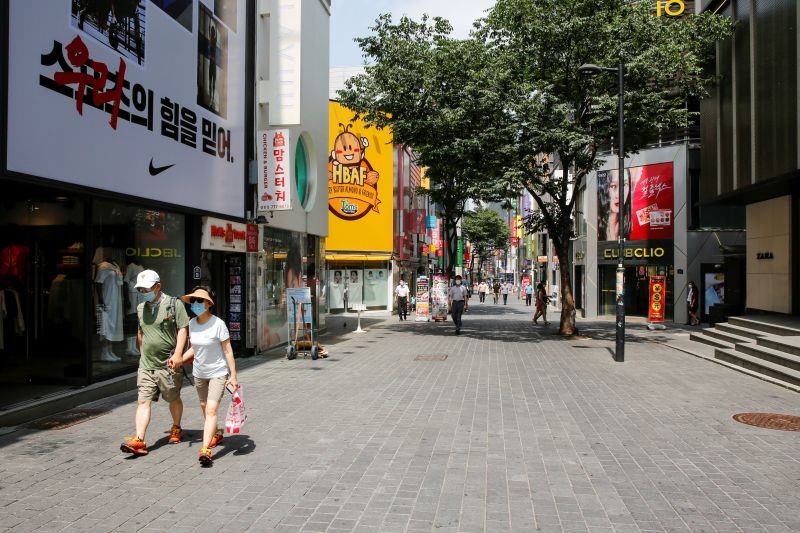 A couple wearing protective masks walk at Myeongdong shopping district, as social distancing measures were introduced to avoid the spread of the coronavirus disease (COVID-19), in Seoul, South Korea on August 19, 2020. (REUTERS Photo)
