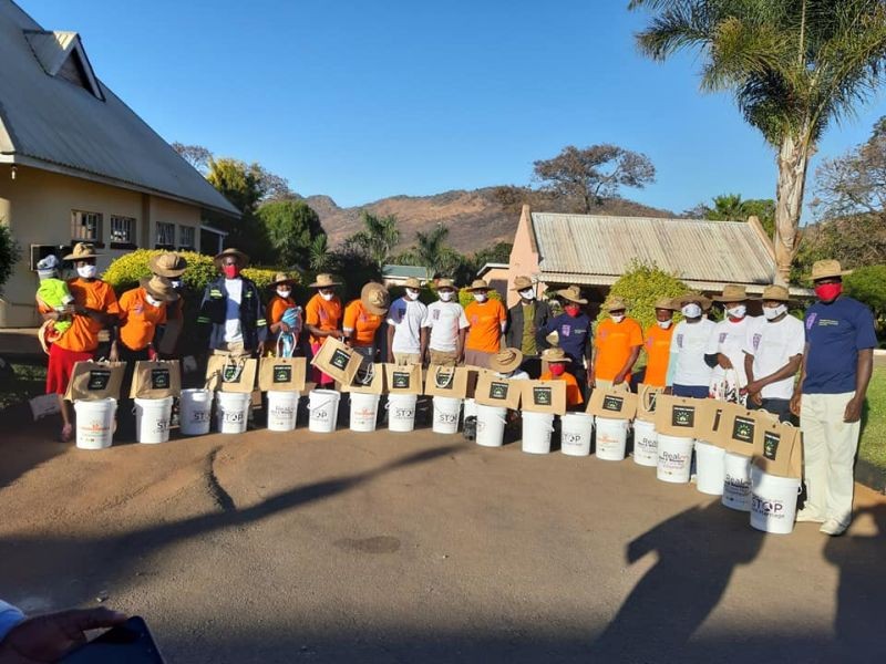 Roots Africa volunteers stand for a photo with buckets used to promote hand washing in Bindura, Zimbabwe on 20 July 2020. (Thomson Reuters Foundation File Photo)