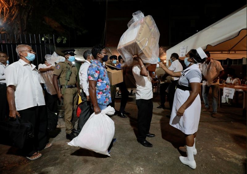 A health official takes the temperature of election officials who arrive with ballot boxes from a polling station to a counting center, after the voting ended during the country's parliamentary election in Colombo, Sri Lanka on August 5, 2020. (REUTERS Photo)