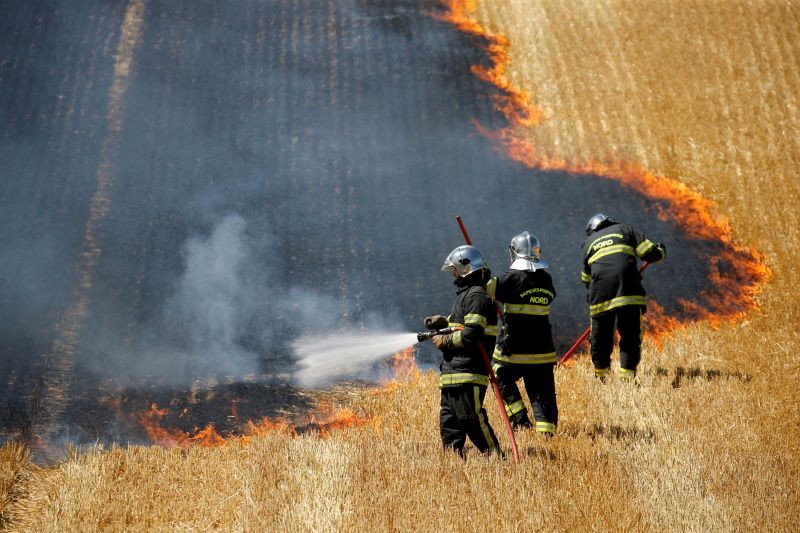French firefighters extinguish a fire in a burning field of wheat during harvest season in Aubencheul-au-Bac, France on July 21, 2020. (REUTERS File Photo)