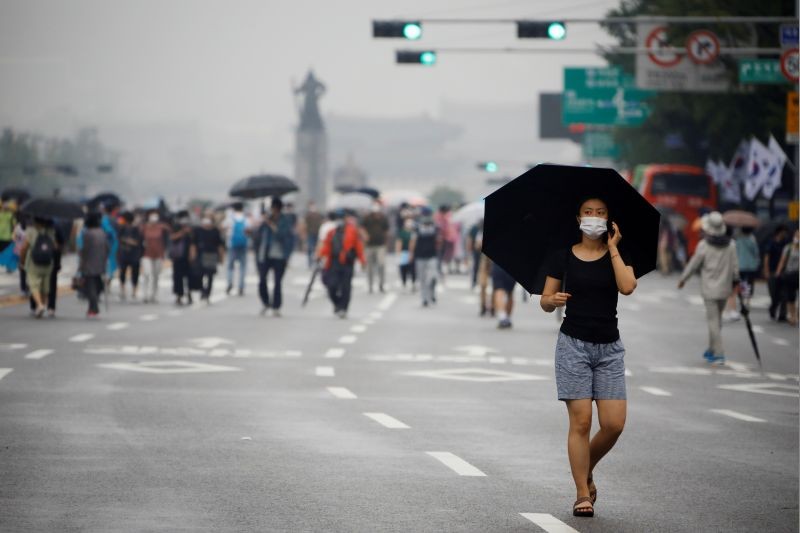 A woman wearing a mask walks past members of conservative civic groups who take part in an anti-government protest, as concerns over a fresh wave of the coronavirus disease (COVID-19) cases grow, in central Seoul, South Korea on August 15, 2020.    (REUTERS Photo)