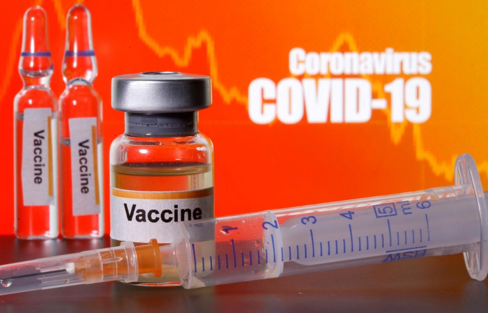 FILE PHOTO: Small bottles labeled with "Vaccine" stickers stand near a medical syringe in front of displayed "Coronavirus COVID-19" words in this illustration taken April 10, 2020. REUTERS/Dado Ruvic