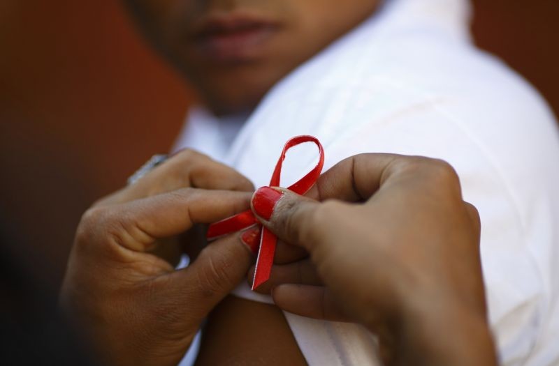 A red ribbon is put on the sleeves of a man by his friend to show support for people living with HIV during a program to raise awareness about AIDS on World AIDS Day in Kathmandu December 1, 2013. (REUTERS File Photo)