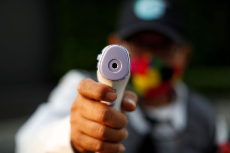 A security guard points a thermometer gun as he stands at the entrance of a condominium building, amid the coronavirus disease (COVID-19) outbreak, in Bangkok, Thailand on April 30, 2020. (REUTERS File Photo)
