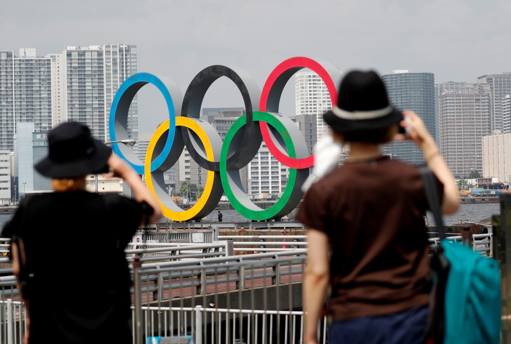 FILE PHOTO: Women look at the giant Olympic rings, which are being temporarily removed for maintenance, amid the coronavirus disease (COVID-19) outbreak, at the waterfront area at Odaiba Marine Park in Tokyo, Japan August 6, 2020. REUTERS/Kim Kyung-Hoon/File Photo)