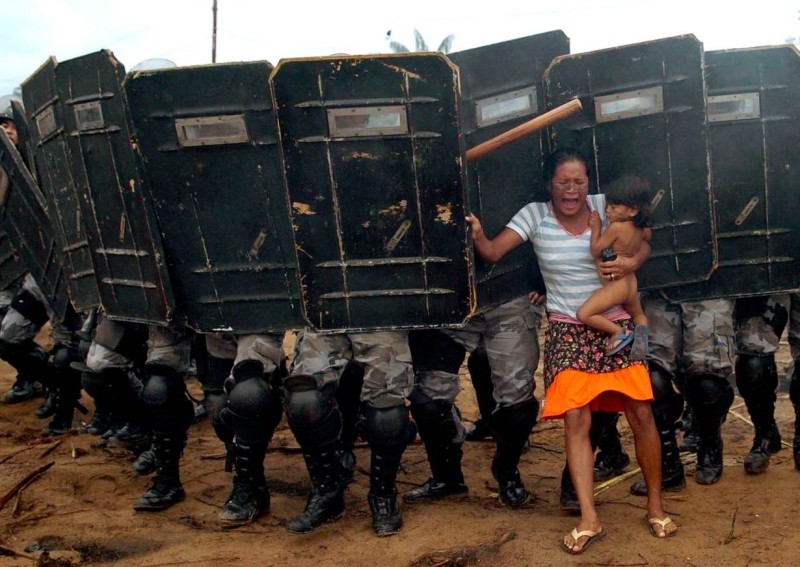 An indigenous woman holds her child while trying to resist the advanAn indigenous woman holds her child while trying to resist the advance of Amazonas state policemen who were expelling the woman from land on the outskirts of Manaus, in the heart of the Brazilian Amazon March 11, 2008. (Reuters File Photo)ters File Photo)