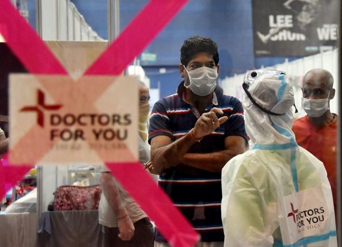 Health worker in PPE kit interacts with a COVID-19 patient at the Commonwealth Games (CWG) Village sports complex, temporarily converted into a COVID care centre, in New Delhi on Wednesday. Photograph: Rahul Singh/ANI Photo