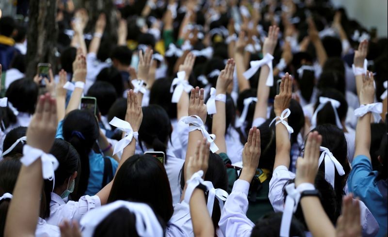 Students wearing white ribbons on their hair and wrists make the three-finger salute to show support for the student-led democracy movement outside the Education Ministry in Bangkok, Thailand on August 19, 2020. (REUTERS File Photo)