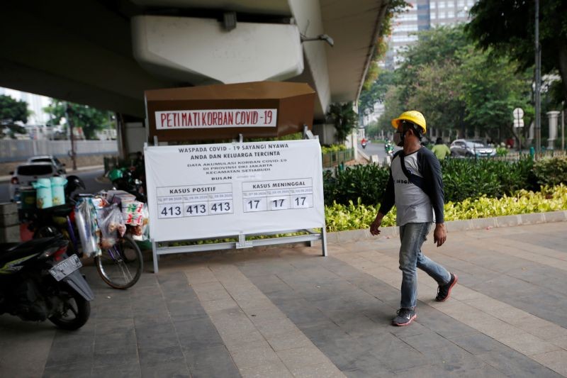 A worker wearing a protective mask walks past a mockup coffin of a COVID-19 victim displayed on the sidewalk of a road to encourage adherence to health protocols, as the coronavirus disease (COVID-19) outbreak continues in Jakarta, Indonesia on September 10. (REUTERS Photo)