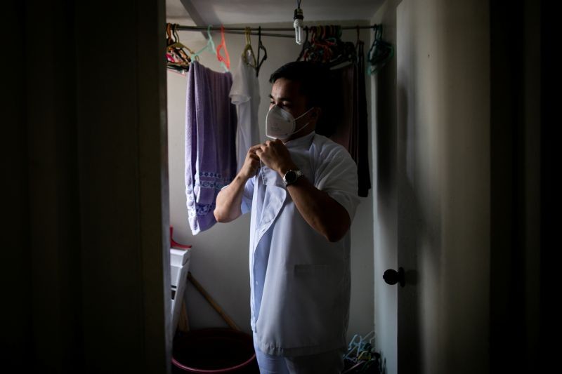 Jordan Jugo, a nurse prevented from leaving the Philippines by a government restriction on health workers' movements, puts on his Philippine hospital work uniform at an apartment he shares with two roommates, in Mandaluyong City, Metro Manila, Philippines on September 4, 2020. "It seems (the government) doesn't really value our contributions. It hurts", he said. (REUTERS File Photo)