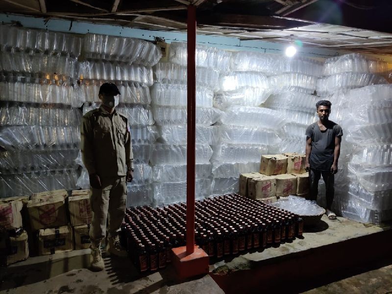 The arrested person along with the seized empty bottles and IMFL.