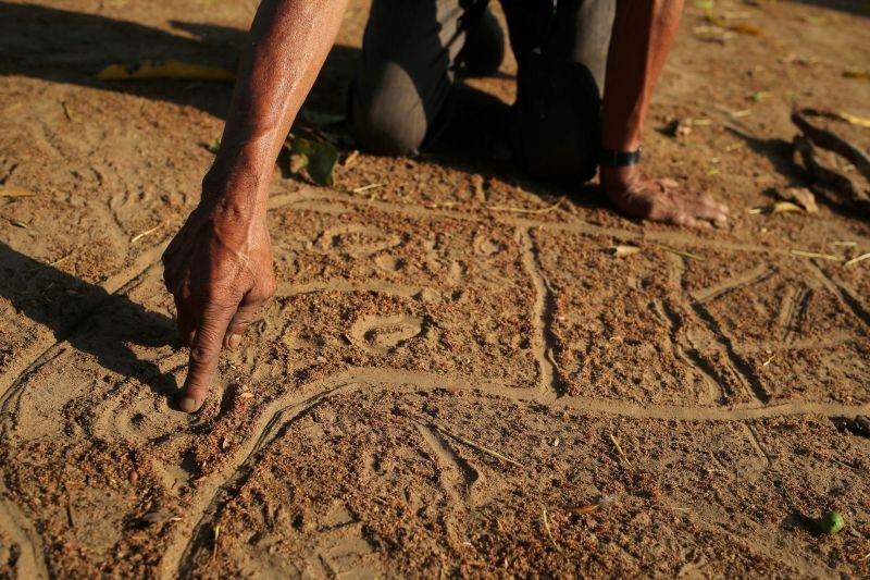 Manoel Kanunxi, chief of the Manoki indigenous people, points to the location of his people's land that was burnt, on a map drawn in dirt, on the outskirts of Brasnorte, in Mato Grosso state, Brazil on August 27, 2019. (REUTERS File Photo)