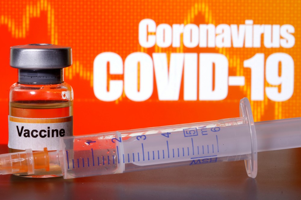 FILE PHOTO: A small bottle labeled with a "Vaccine" sticker stands near a medical syringe in front of displayed "Coronavirus COVID-19" words in this illustration taken April 10, 2020. REUTERS/Dado Ruvic/Illustration
