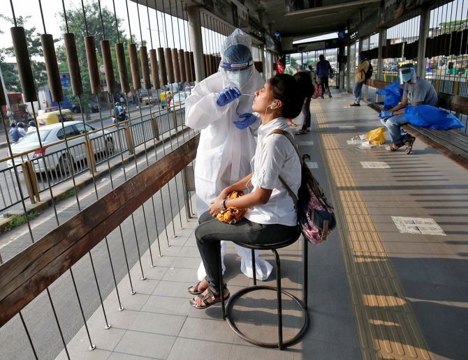 A healthcare worker takes swab from a woman for a rapid antigen test at a bus terminal, in Ahmedabad. Photograph: Amit Dave/Reuters