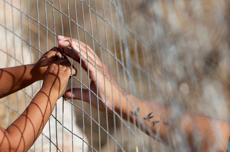 A woman touches hands of a child through a fence at a new temporary camp for migrants and refugees, on the island of Lesbos, Greece on September 22, 2020. (REUTERS Photo)