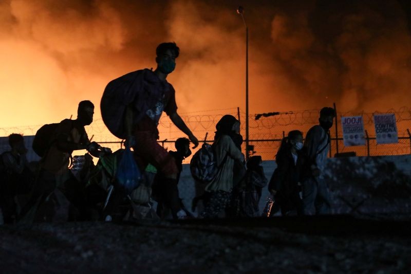 Refugees and migrants carry their belongings as they flee from a fire burning at the Moria camp, on the island of Lesbos, Greece on September 9, 2020. (REUTERS Photo)