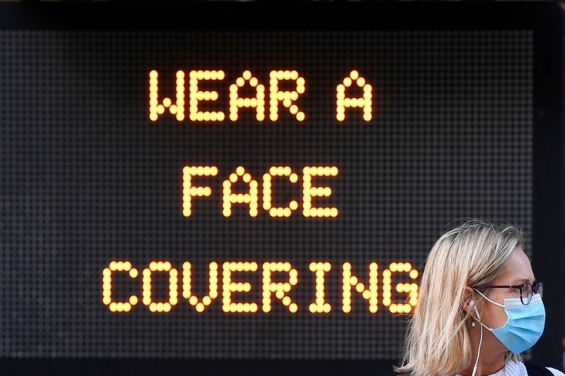 A woman wears a protective face mask as she walks past an information sign at the financial district of Canary Wharf in London, Britain on September 28, 2020. (REUTERS Photo)