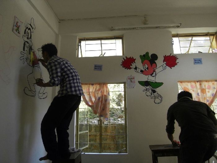 Members of SpeakGuru Foundation painting images of cartoon characters on the walls to brighten the mood in the Oncology Unit at NHAK.