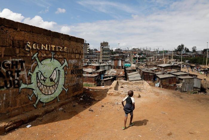 A boy walks in front of a graffiti promoting the fight against the coronavirus disease in the Mathare slums of Nairobi, Kenya, May 22, 2020. REUTERS/Baz Ratner