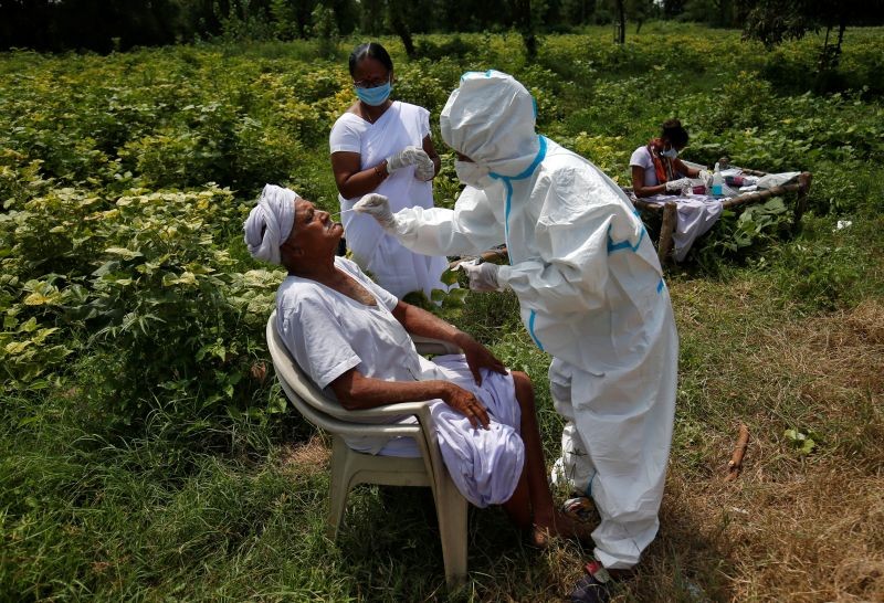 A healthcare worker wearing personal protective equipment (PPE) takes swabs from a farmer in a field, amidst the coronavirus disease (COVID-19) outbreak, in Kavitha village in Gujarat on September 15, 2020. (REUTERS Photo)