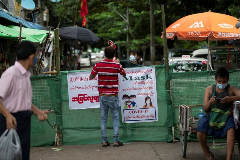 A woman passes a package to a man behind a makeshift barricade, blocking off a street to prevent the spread of the coronavirus disease (COVID-19) in Yangon, Myanmar on September 12, 2020. (REUTERS File Photo)