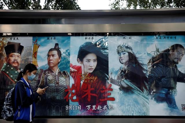 A woman walks past an advertisement promoting Disney's movie "Mulan" at a bus stop in Beijing, China. (Reuters Photo)