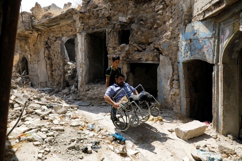 Mohammed Sattar, an Iraqi man who says that he lost his both legs during the battle to retake Mosul from Islamic State militants, sits in a wheelchair as he is seen next to his destroyed house in the old city of Mosul, Iraq on August 31, 2020. (REUTERS File Photo)
