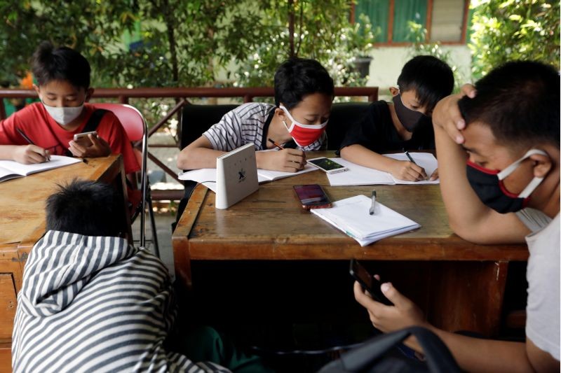 Dimas Anwar Saputra, a 15-year-old junior high school student, wearing a red protective mask, studies with other students using free internet wifi access that they got by exchanging plastic waste, amid the coronavirus disease (COVID-19) outbreak, at a local district office in Jakarta, Indonesia on September 9, 2020. (REUTERS Photo)