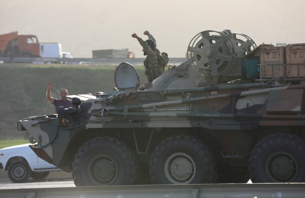 FILE PHOTO: An Azerbaijani service member drives an armoured carrier and greets people, who gather on the roadside in Baku, Azerbaijan September 27, 2020. REUTERS/Aziz Karimov/File photo