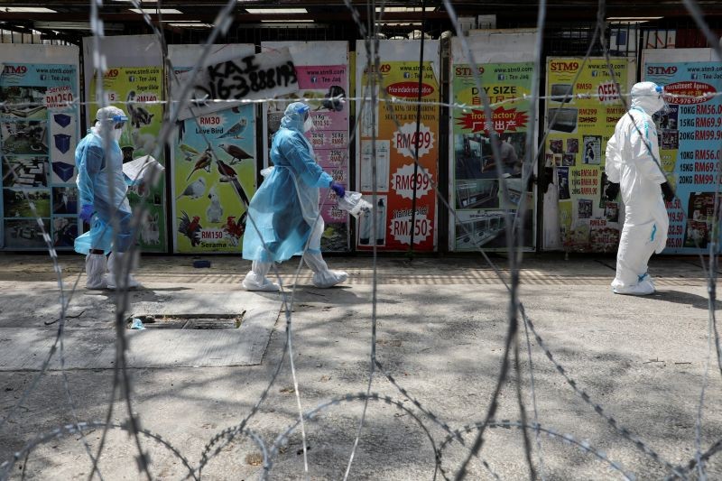 Medical workers wearing protective suits pass by barbed wire in a red zone under enhanced lockdown, amid the novel coronavirus outbreak, in Petaling Jaya, Malaysia on May 11, 2020. (REUTERS File Photo)