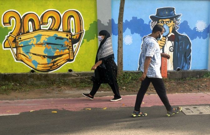 People walk past in front of wall graffiti paint to create an awareness during ongoing coronavirus pandemic, in Bhubaneswar. Photograph: ANI Photo