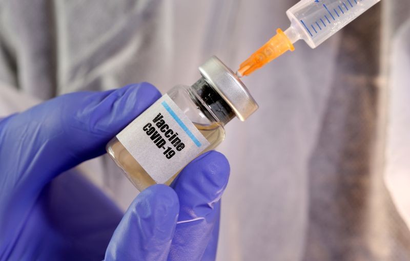 A woman holds a small bottle labeled with a "Vaccine COVID-19" sticker and a medical syringe in this illustration taken on April 10, 2020. (REUTERS File Photo)