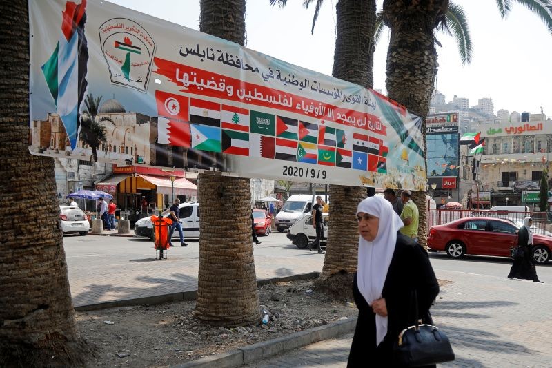 A banner showing Arab countries's flags is seen as a woman walks during a protest against normalizing ties with Israel, in Nablus in the Israeli-occupied West Bank, as Arab foreign ministers meet on September 9, 2020. (REUTERS Photo)