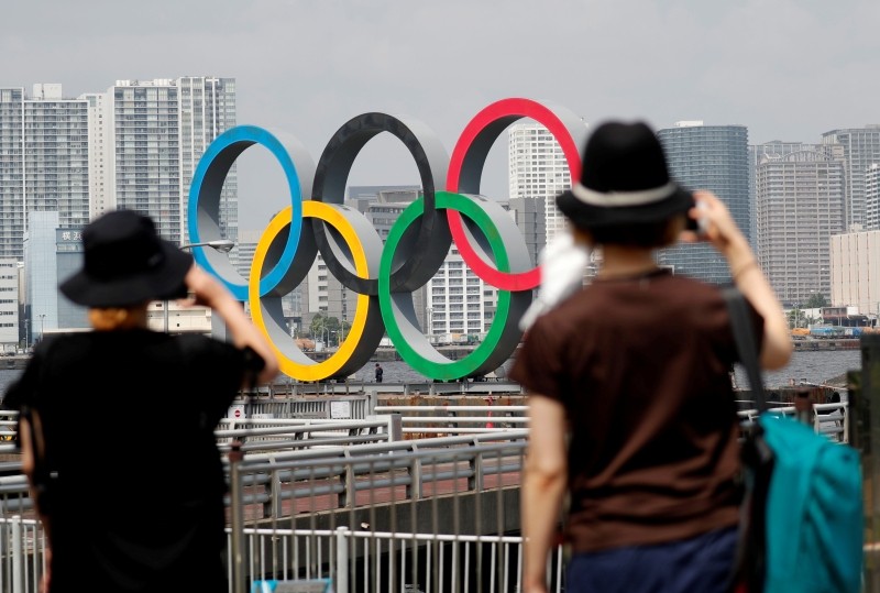 FILE PHOTO: Women look at the giant Olympic rings, which are being temporarily removed for maintenance, amid the coronavirus disease (COVID-19) outbreak, at the waterfront area at Odaiba Marine Park in Tokyo, Japan August 6, 2020. REUTERS/Kim Kyung-Hoon/File Photo