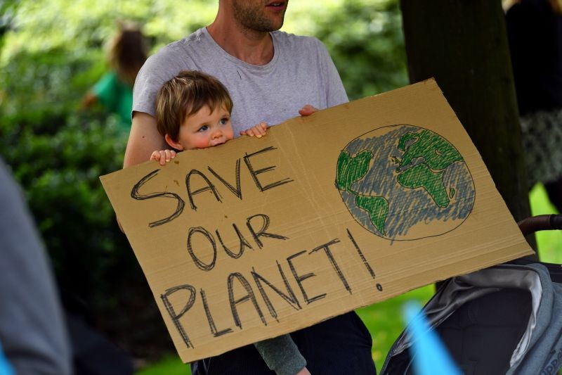 A father and his child are holding a sign as climate activists protest outside the Shell building in London, Britain on September 8, 2020. (REUTERS Photo)