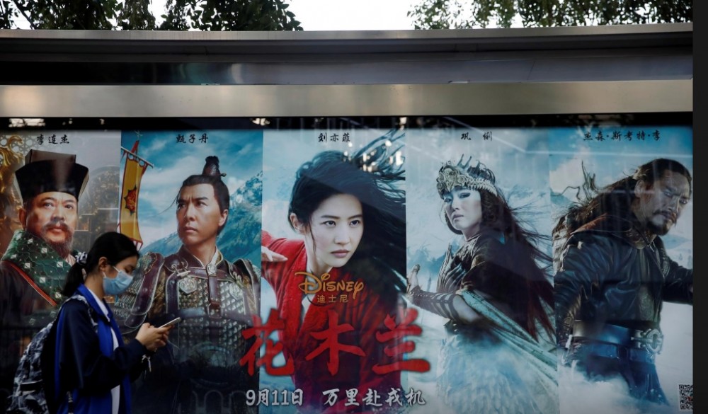 A woman walks past an advertisement promoting Disney's movie "Mulan" at a bus stop in Beijing, China September 9, 2020. REUTERS/Carlos Garcia Rawlins