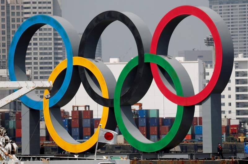 FILE PHOTO: The giant Olympic rings, which are being temporarily removed for maintenance, are seen behind Japan's national flag, amid the coronavirus disease (COVID-19) outbreak, at the waterfront area at Odaiba Marine Park in Tokyo, Japan August 6, 2020. REUTERS/Kim Kyung-Hoon/File Photo