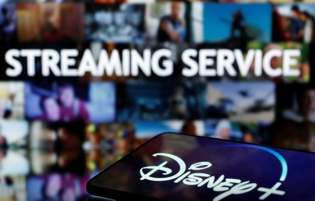 A smartphone with displayed "Disney" logo is seen in front of displayed "Streaming service" words in this illustration taken March 24, 2020. REUTERS/Dado Ruvic