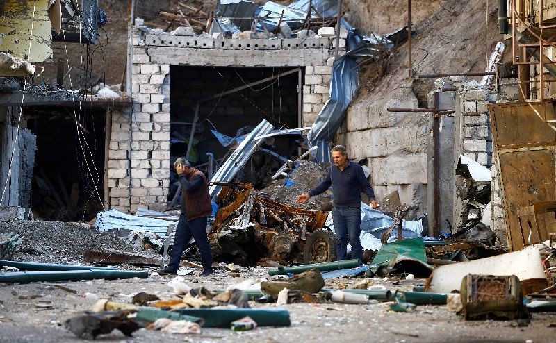 Men are seen among the ruins after recent shelling during the military conflict over the breakaway region of Nagorno-Karabakh, in Stepanakert October 13, 2020. REUTERS/Stringer