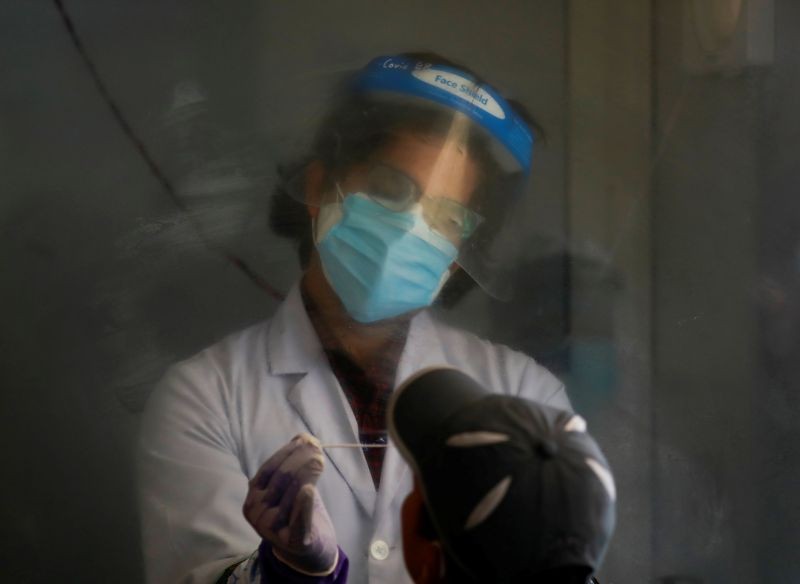 A health worker inside a booth collects swap from a man as he takes a polymerase chain reaction (PCR) test for the coronavirus disease (COVID-19) in Kathmandu, Nepal October 9, 2020. (REUTERS File Photo)